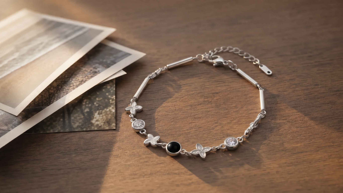 A Four-Leaf Clover photo projection bracelet on a walnut table beside a fan of printed photographs in warm afternoon light