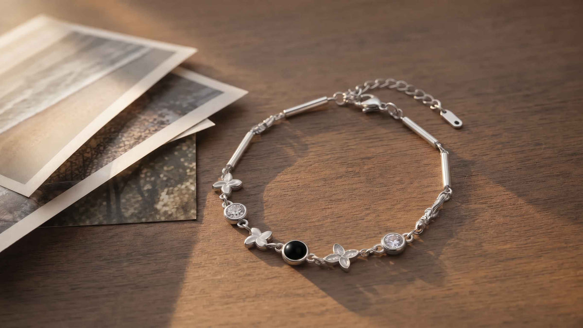 A Four-Leaf Clover photo projection bracelet on a walnut table beside a fan of printed photographs in warm afternoon light