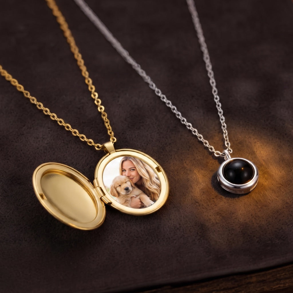 A photo projection pendant beside an open photo locket on dark velvet, warm light glowing through the projection lens