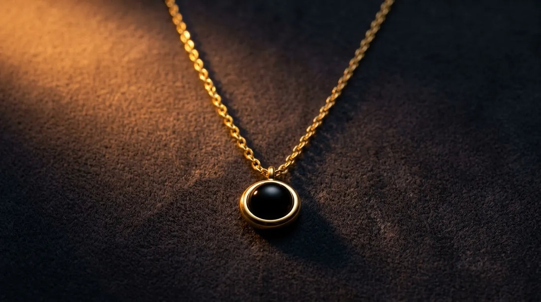 Round photo projection necklace with a deep black lens resting on charcoal velvet in warm light