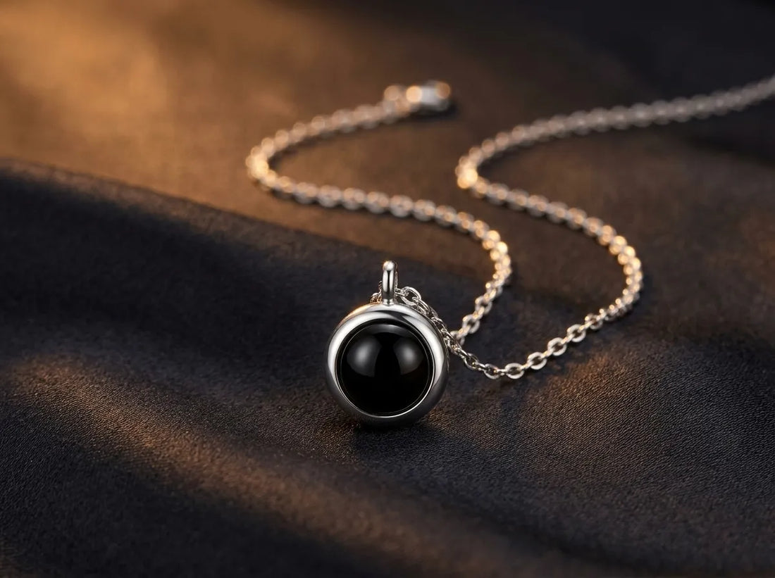 Round photo projection pendant with a deep black optic, resting on charcoal velvet in warm light
